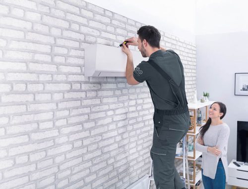 Male Technician Repairing Air Conditioner With Screwdriver Smiling Woman Looking At Male Technician Repairing Air Conditioner With Screwdriver In Home
