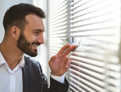 The happy businessman looking through the blinds The happy businessman looking through the blinds